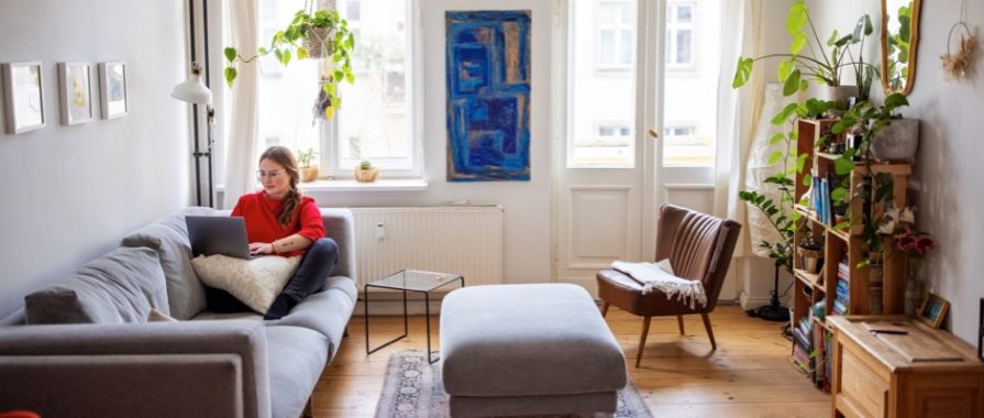 Young businesswoman sitting on couch and working on laptop computer. Female working at home using laptop.