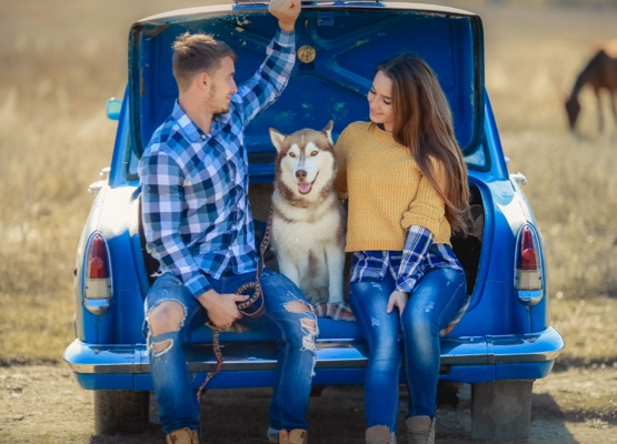 Portrait of a young family with a dog near a convertible