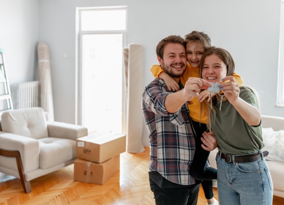 Excited American young family show keys to own home, happy couple buying first house together, smiling husband and wife purchase new property.