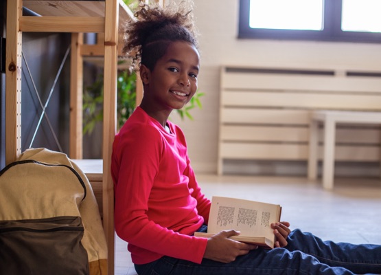 Portrait of African American girl sitting on the floor and reading a book