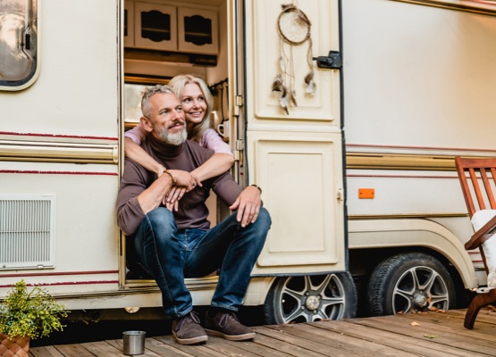 Aged happy couple sitting in the van doorway and hugging with love
