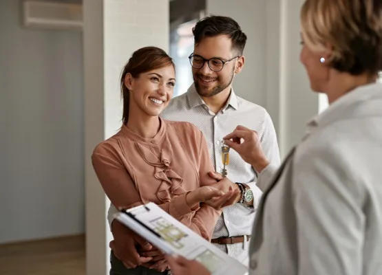 Young happy couple receiving keys of their new home from real estate agent.
